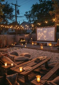 an outdoor movie is set up in the backyard with candles and pillows on the ground