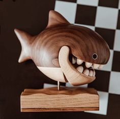 a wooden sculpture of a shark with its mouth open on a checkered wall background