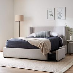 a bed sitting on top of a wooden floor next to a lamp and a rug