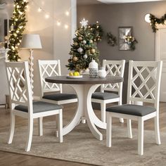 a dining room table with four chairs and a christmas tree in the corner behind it