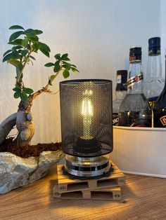 a lit candle sitting on top of a wooden table next to a potted plant