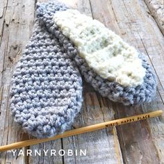 two crocheted mittens sitting on top of a wooden table next to a pencil