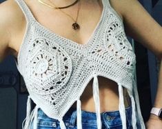 a woman wearing a crochet top with fringes on her chest and one hand in her pocket