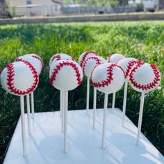 several baseballs are on top of white sticks with red stitching in the middle