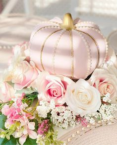 a pink hat with flowers and pearls on it is sitting next to a flower arrangement