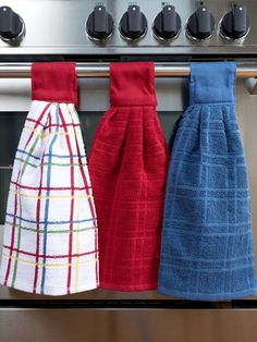 three kitchen towels hanging on the rack in front of an oven door with knobs