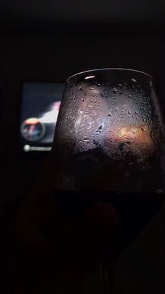 a wine glass with water on it and a cell phone in the backround