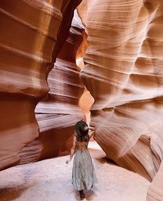 a woman is standing in the middle of a slot canyon and looking up into the sky