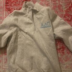 a gray sweatshirt with the letters aa on it laying on a red carpet next to a rug