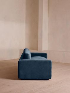 a blue couch sitting on top of a hard wood floor next to a white wall