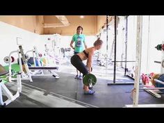 two women doing squats in a crossfit gym with one holding a barbell