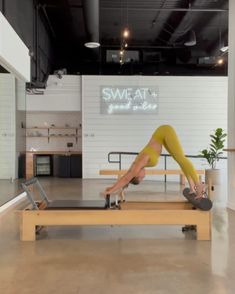 a woman in yellow pants is doing a pivot on a wooden bench with a laptop