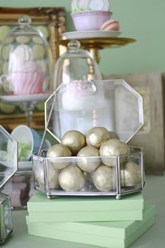 there is a glass container filled with balls on top of some green books in front of cupcakes