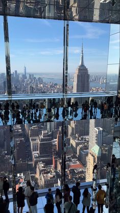 people are standing on the glass walkway in front of the empire building, looking down at the city