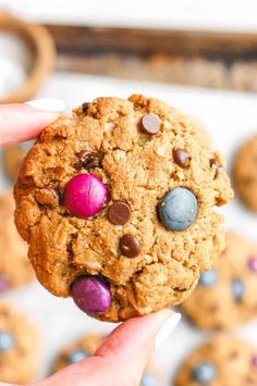 a hand holding a cookie with chocolate chips and candy