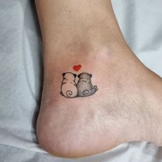 a small tattoo on the foot of a person with a teddy bear holding a heart