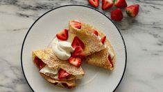 two crepes on a plate with strawberries and whipped cream next to them