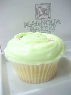 a cupcake with green frosting sitting on a white plate next to a sign