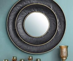 two black and gold plates sitting next to each other on top of a table in front of a mirror