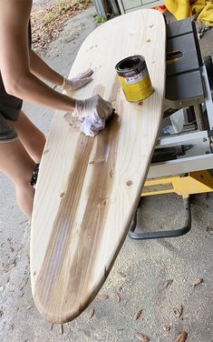 a person is sanding up a surfboard on the ground next to a table