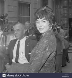 an old photo of a woman standing next to a man in front of a building