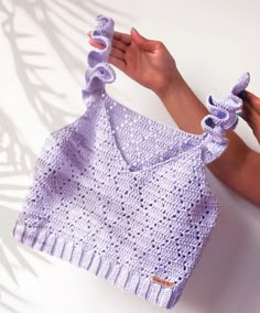 a hand holding up a purple crocheted bag with ruffles on it