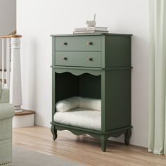 a green cabinet with white pillows on it in a living room next to a couch