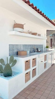 an outdoor kitchen with white cabinets and tile flooring on the side of a building