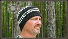 a man wearing a black and white knitted hat in front of some tall trees