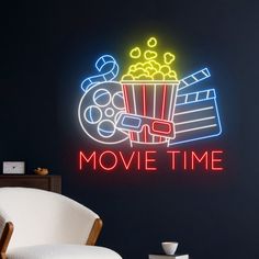 a neon sign that says movie time in front of a white chair and black wall