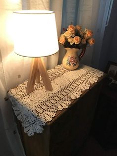 a table with a lamp on top of it next to a vase filled with flowers