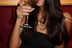 a woman holding a martini glass with olives in it