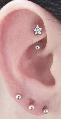 a woman's ear with three piercings on it