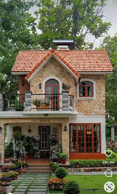 a small house with lots of windows and plants in the front yard, surrounded by greenery