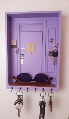 a purple door with sunglasses and keys hanging from it's sides on a wall