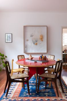 a dining room table with chairs around it and a rug on the floor in front of it