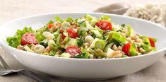 a white bowl filled with salad next to a fork