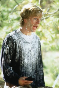 the young man is covered in mud while holding a cell phone and looking at something