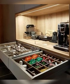 an open drawer in a kitchen filled with coffee and other items on top of a counter