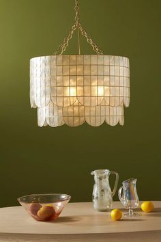 a chandelier hanging from the ceiling over a table with bowls and pitchers on it