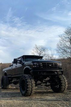 a large black truck parked on top of a dirt field