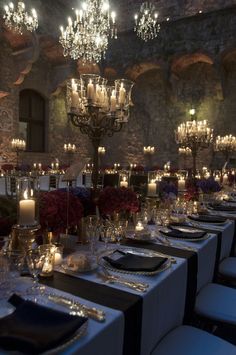 a table set for dinner with candles and flowers in the center, surrounded by chairs