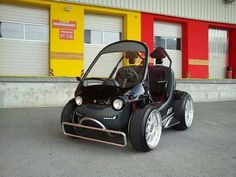 an electric golf cart is parked in front of a yellow and red building with two doors