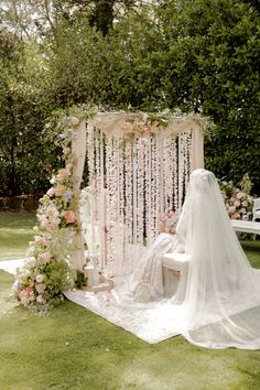 an outdoor wedding ceremony setup with flowers and petals on the aisle, draped in white fabric