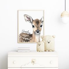 a white dresser topped with a stuffed animal next to a framed deer print on the wall