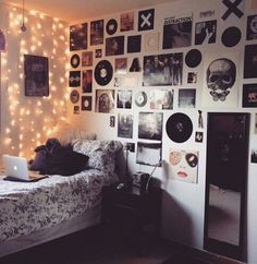 a bed room with a laptop computer on top of it next to a wall covered in pictures