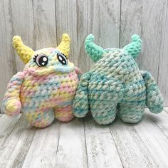 two crocheted stuffed animals sitting next to each other on a white wooden surface