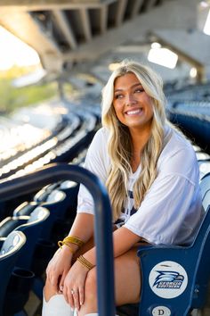 a woman sitting in the bleachers at a baseball game with her legs crossed