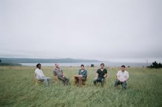 four people sitting in the middle of a field