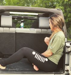 a woman sitting in the back of a pick up truck with her feet on the ground